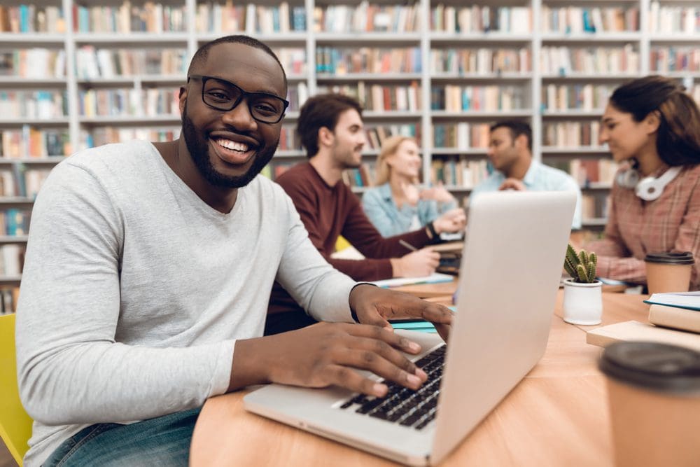 Man In Library On Computer Smiling